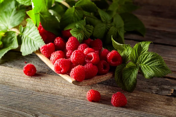 Eski ahşap arka planda yaprakları olan taze ahududular..