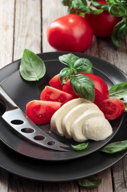 Eski ahşap bir masada domates ve fesleğenli Mozzarella..