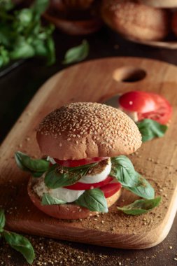 Eski ahşap bir masada mozarella, domates ve fesleğenli sandviç..