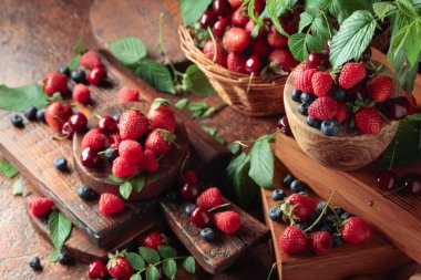 Yapraklı taze böğürtlen. Eski bir masada çilek, ahududu, yabanmersini ve tatlı kirazlar.. 