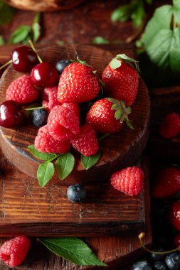 Yapraklı taze böğürtlen. Eski bir masada çilek, ahududu, yabanmersini ve tatlı kirazlar.. 