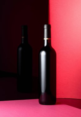 Açılmamış kırmızı şarap şişesi, parlak siyah yüzeyi yansıtıyor..