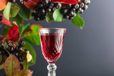 Bir bardak böğürtlen likörü. Koyu arkaplanda yaprakları olan taze meyveler.. 