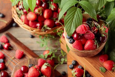 Yapraklı taze böğürtlen. Çilek, ahududu, böğürtlen ve kirazlar eski ahşap bir masada.. 
