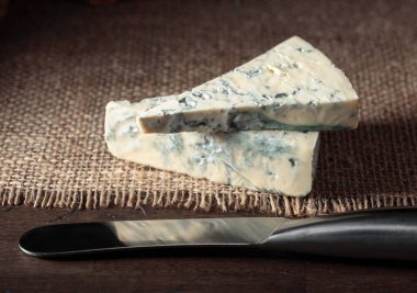 Eski ahşap bir masada mavi peynir ve peynir bıçağı..