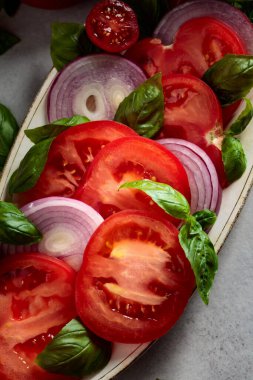 Mutfak masasında domatesli salata, fesleğen ve kırmızı soğan..