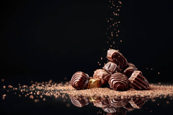 Шоколадные конфеты на черном фоне, посыпанные шоколадной крошкой. Копирование пространства.