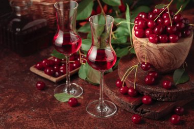 Kahverengi bir masada kiraz likörü ve olgun meyveler..