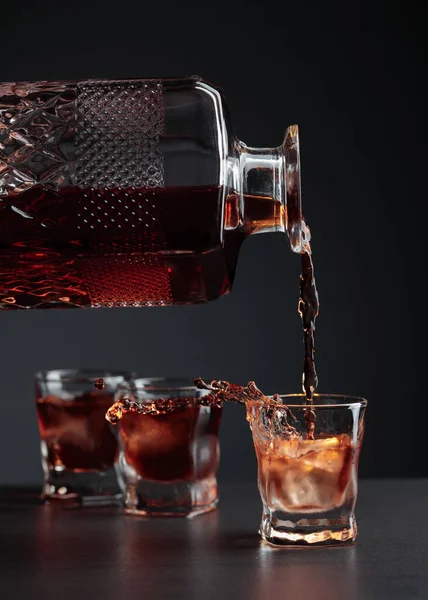 ウィスキーが氷を入れたフローストグラスに注ぐ アルコール飲料はクリスタルデカンタからガラスに注がれます — ストック写真