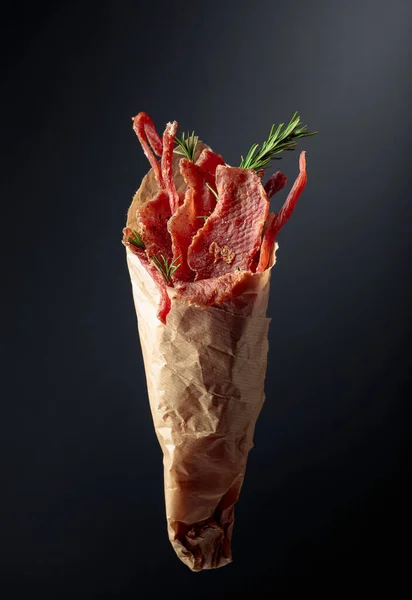 Slices Spicy Dry Cured Meat Rosemary Paper Bag Dark Background — Stock Photo, Image