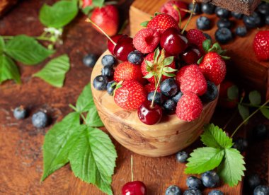 Yapraklı taze böğürtlen. Eski bir masada çilek, ahududu, yabanmersini ve tatlı kirazlar.. 