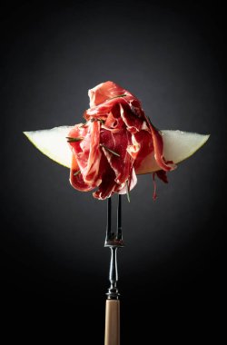 Prosciutto ve biberiyeli kavun. Kopyalama alanı olan siyah arkaplan.