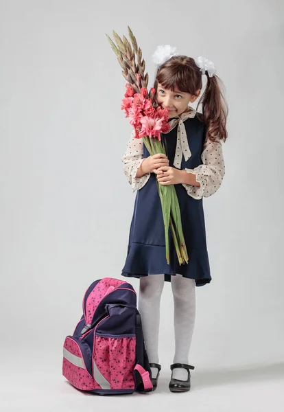 小学校の制服姿の少女の肖像画 リュックと花を持つ1年生 スペースのコピー — ストック写真