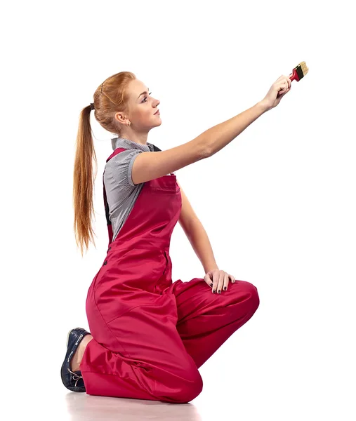 Young woman in red overalls with brush — Stock Photo, Image