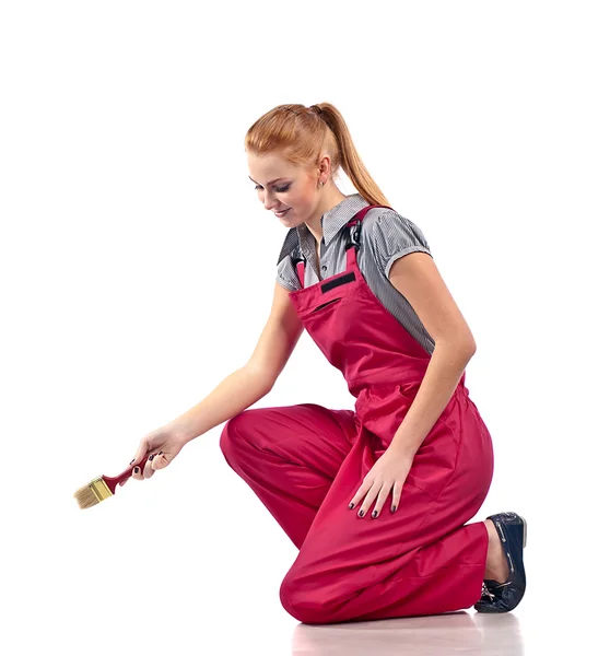 Young woman in red overalls with brush — Stock Photo, Image