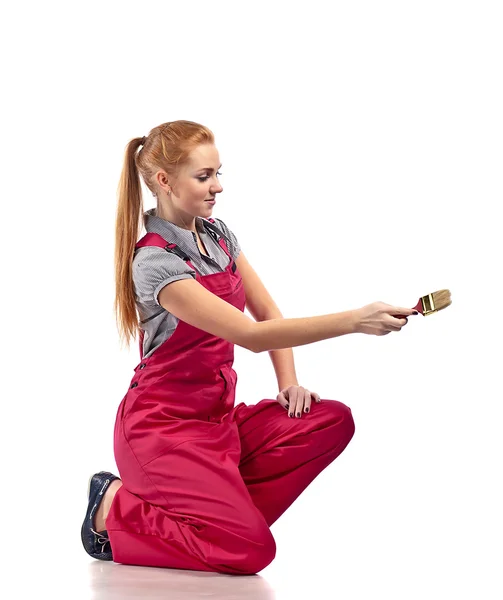 Young woman in red overalls with brush — Stock Photo, Image