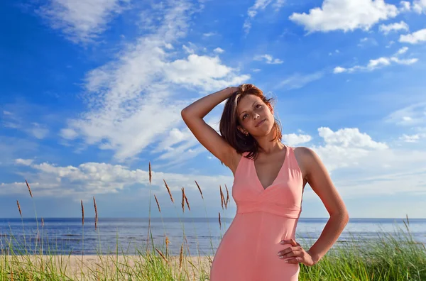 Sahil üzerinde pembe elbiseli kadın — Stok fotoğraf