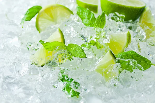 Trozos de lima y hojas de menta con hielo — Foto de Stock