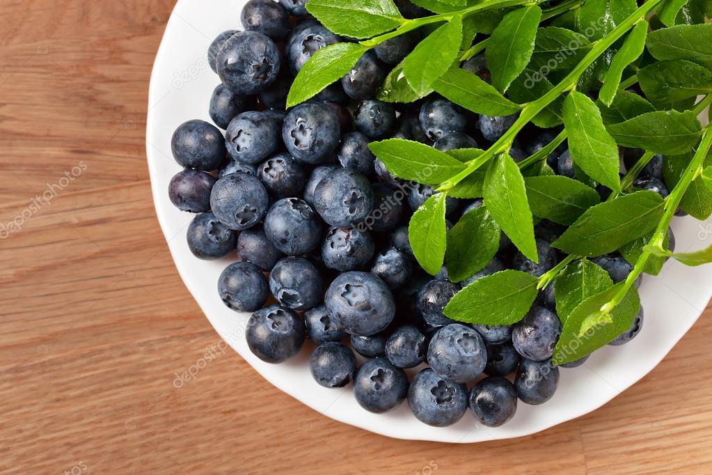 blueberry, ripe berries and green leaves on wooden table — 图库