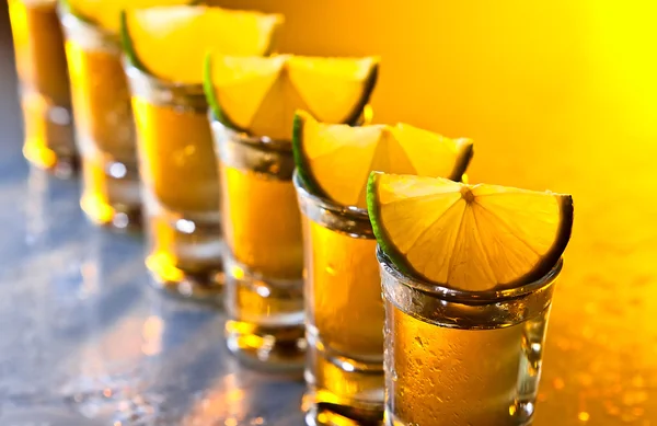 Tequila en kalk op glazen tafel — Stockfoto