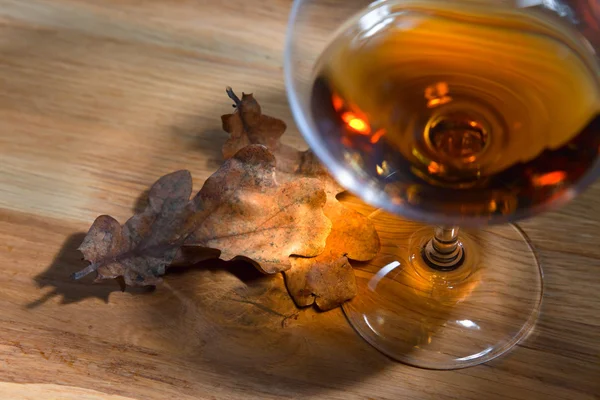 Brandy and dried oak leaves — Stock Photo, Image