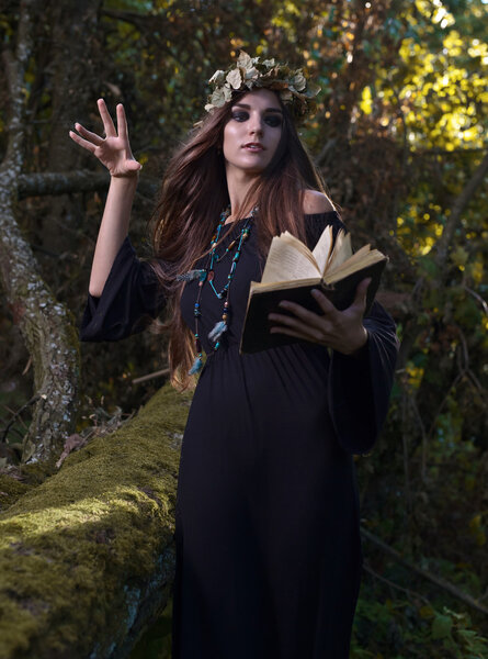 The young beautiful woman with book in dark forest