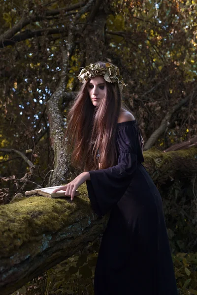 Woman with book in dark forest — Stock Photo, Image