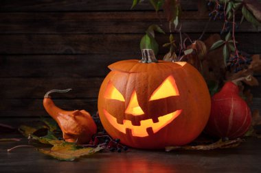 Kurumuş yapraklı balkabağı kafalı balkabağı feneri. Cadılar Bayramı sanat tasarımı, kutlama. Kavurucu mumla oyulmuş Cadılar Bayramı balkabağı.