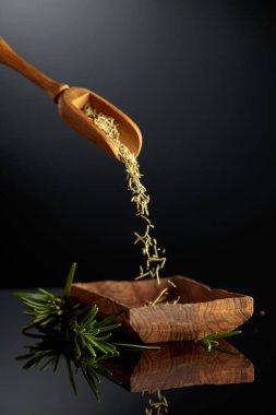 Siyah yansıtıcı arka planda biberiye. Kuru biberiye ahşap bir kaseye dökülür..