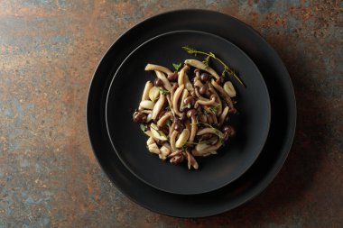 Siyah tabakta kekik ve sarımsaklı kızarmış shimeji mantarı. Geleneksel Japon mutfağı.