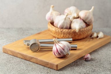 Tahta kesme tahtasına sarımsak ve sarımsak ezici yakın plan..