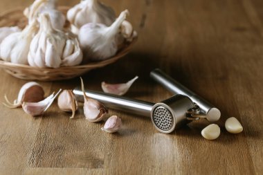 Garlic bulbs and garlic press on an old wooden table. 