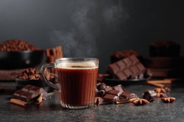 Siyah mutfak masasının üzerinde malzemeler olan bir bardak sıcak çikolata. Boşluğu kopyala.