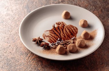 Chocolate truffles on a beige plate with chocolate sauce. Copy space.