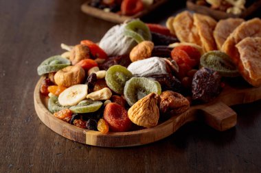 Kurutulmuş tropikal meyve, fındık ve kuru üzümlerin karışımı eski bir ahşap masada..