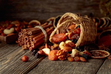 Eski ahşap bir masada kurumuş meyve ve fındık. Kurutulmuş turunçgiller, kayısılar, kuru üzümler, çeşitli fındıklar, tarçın çubukları ve anason..