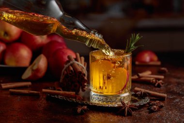 Elma kombu çayı şişeden kristal bardağa dökülür. Eski bir mutfak masasında elmalı taze içecek. Boşluğu kopyala.