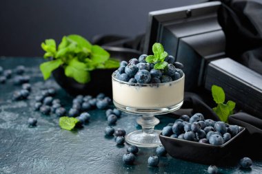 Temiz bir kasede taze yaban mersinli panna cotta. Nane şekeriyle süslenmiş çilekli parfüm..