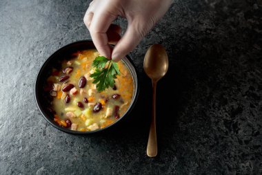 Siyah taş bir masada patates, domates, paprika, havuç ve pastırma ile kırmızı fasulye çorbası. Üst Manzara. Boşluğu kopyala.