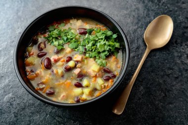 Siyah taş bir masada patates, domates, paprika, havuç ve pastırma ile kırmızı fasulye çorbası. Üst Manzara. Boşluğu kopyala.