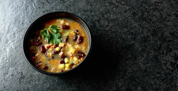 Siyah taş bir masada patates, domates, paprika, havuç ve pastırma ile kırmızı fasulye çorbası. Üst Manzara. Boşluğu kopyala.