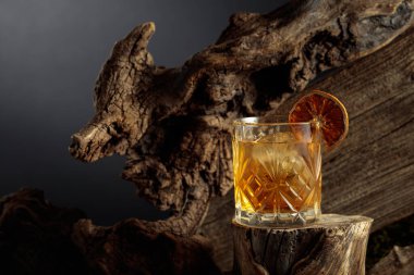 Eski moda bir karışım, buz ve kurutulmuş portakal dilimi ile eski ahşap bir kütükte.. 