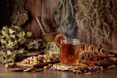 Bir fincan bitkisel çay, çeşitli kurutulmuş bitkiler, çiçekler ve baharatlar. İçindekilerle çay ve kurutulmuş narenciye..