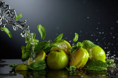 Siyah arka planda limon ve taze nane dalları. Serinletici içecekler ve su sıçraması için gerekli malzemeler. Boşluğu kopyala.