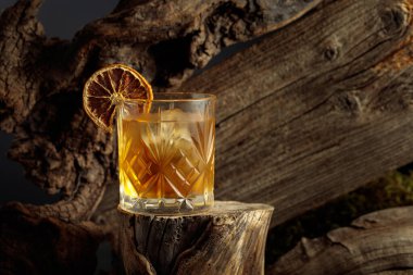 Eski moda bir karışım, buz ve kurutulmuş portakal dilimi ile eski ahşap bir kütükte.. 