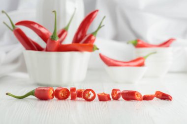 Beyaz ahşap bir masada yeşil saplı taze kırmızı biber. Seçici odak.