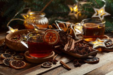 Tarçın, anason ve kuru narenciye dilimli Noel çayı. Eski ahşap bir masada malzemeli bitki çayı..