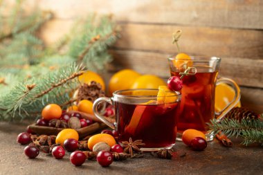 Eski bir mutfak masasında malzemelerle kış içkileri. Masaya dağılmış yabanmersini, kumkat, portakal, anason, tarçın, hindistan cevizi ve karanfil var..