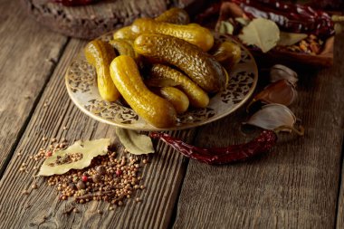 Eski ahşap bir masada lezzetli bir tuzlu su yapmak için malzemeli salatalık turşusu..