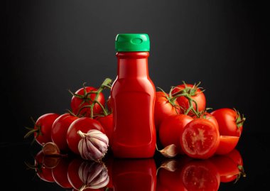 Plastik ketçap şişesi ya da domates sosu, taze domates ve siyah yansıtıcı arka planda sarımsak..